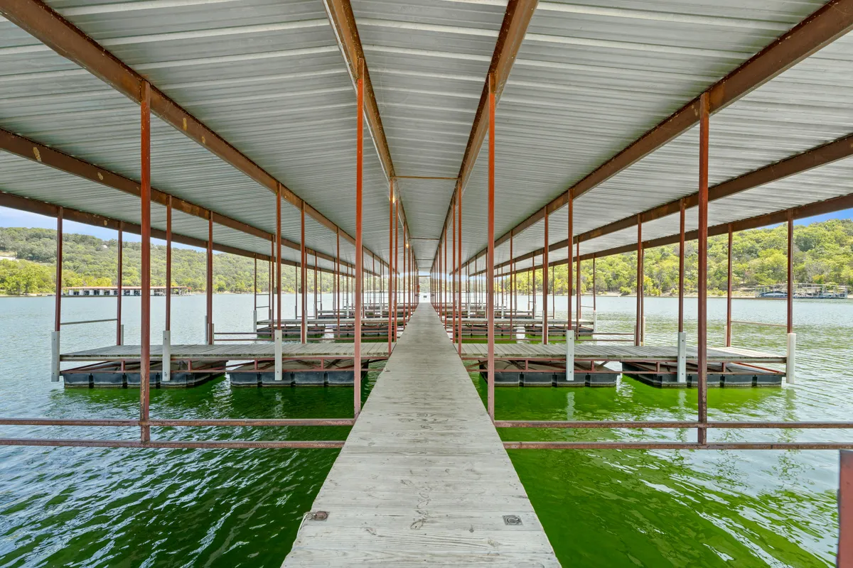 A tranquil lakeside scene featuring a dock that extends into the water, framed by rolling hills in the background. The image captures opportunities for boating, fishing, and taking in sunsets or early morning moments on the water.