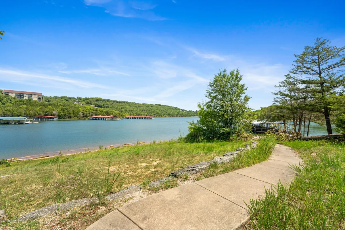 A calm lake bordered by lush green areas and a winding walking path. The scene is inviting for leisurely strolls, picnics, and quiet reflection, with the potential for wildlife sightings along the shore.