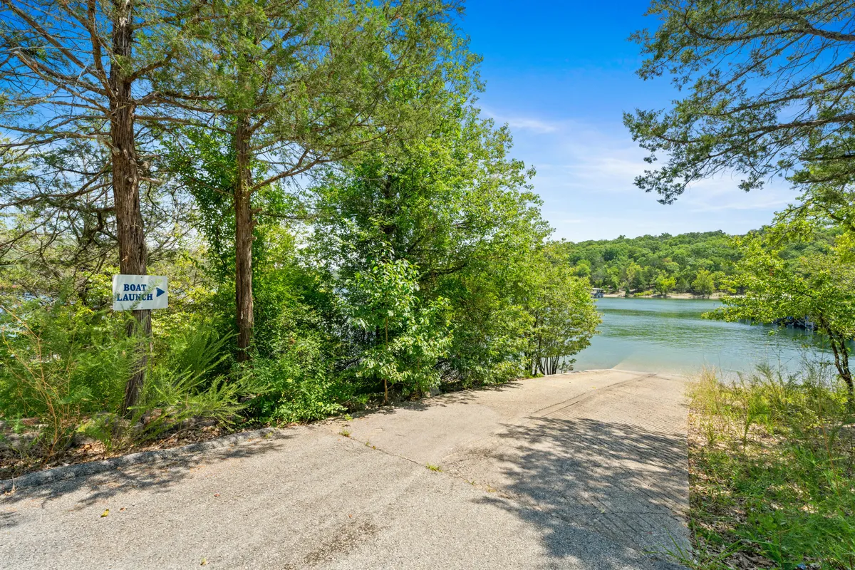 A clear view of the boat launch area, complete with a concrete ramp leading into the lake, surrounded by trees and a visible 'boat launch' sign. The water sparkles invitingly, suggesting readiness for boating or quiet paddling.
